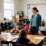 Teacher guiding inclusive classroom with autistic student
