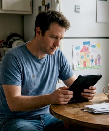 Father reading autism article in kitchen