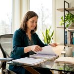 Caregiver organizing autism therapy documents at table