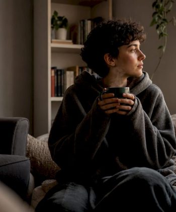 Young adult resting in cozy nook with tea